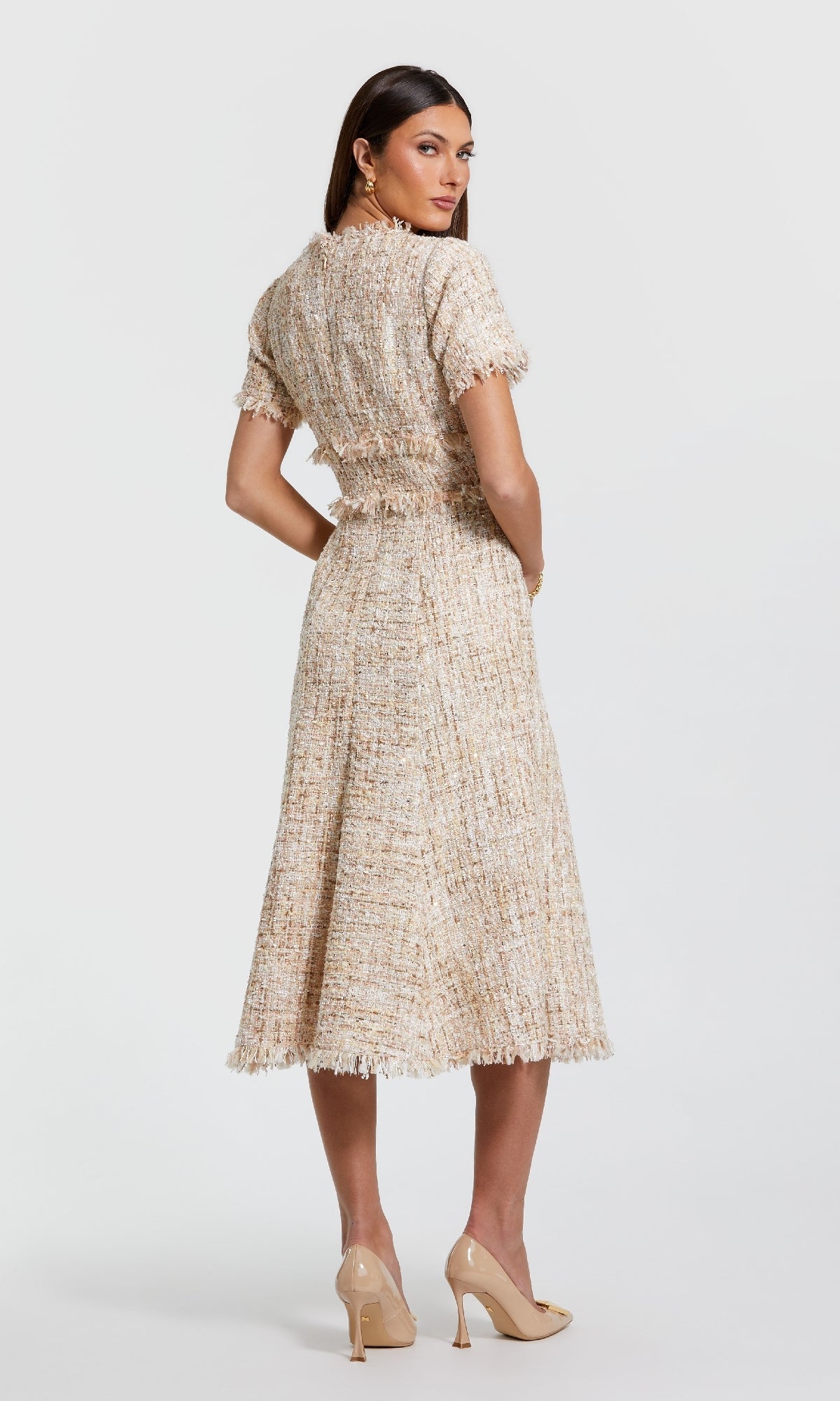 Woman stands facing backward in a semi-formal tea-length Mac Duggal 21045 short-sleeve pink career dress, paired with nude high heels, set against a plain white background.